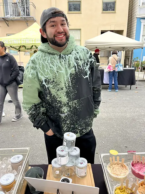 A smiling person behind a stack of Obour jars at the stand