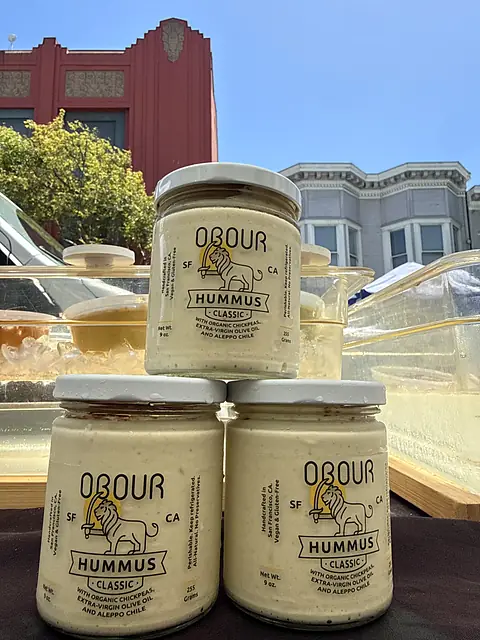 Three jars of Obour Classic hummus stacked on the market table