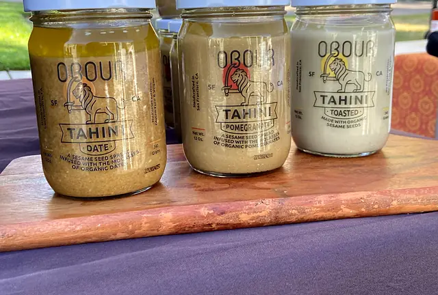 Jars of Obour Date, Pomegranate and Toasted tahini on a wooden board at the market stand