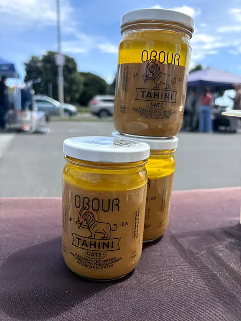 Jars of Obour Date tahini stacked on the market table