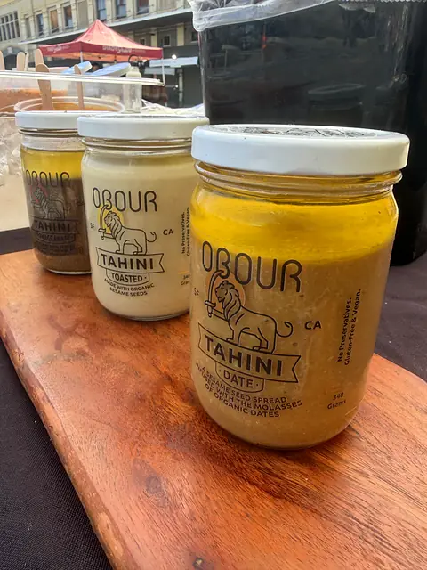 Jars of Obour Date, Toasted and Pomegranate tahini on a wooden board