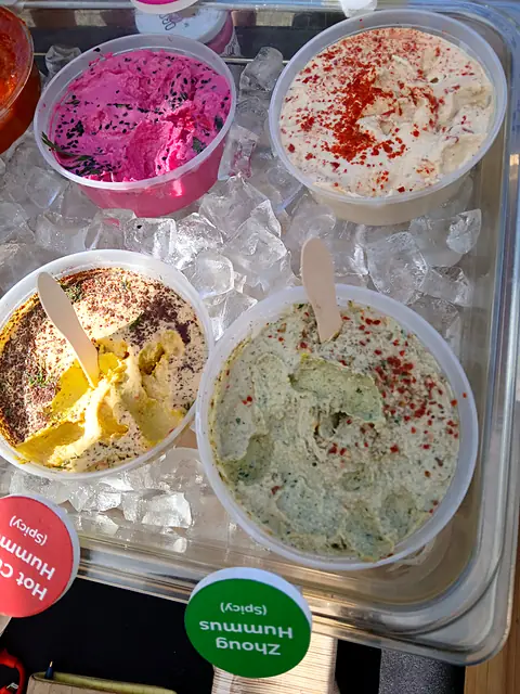 Sample tubs of Red Beet, Classic, Hot Curry and Zhoug hummus on ice