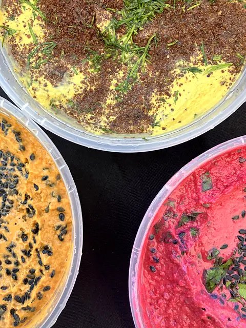 A close-up of garnished Hot Curry, Berbere and Red Beet hummus