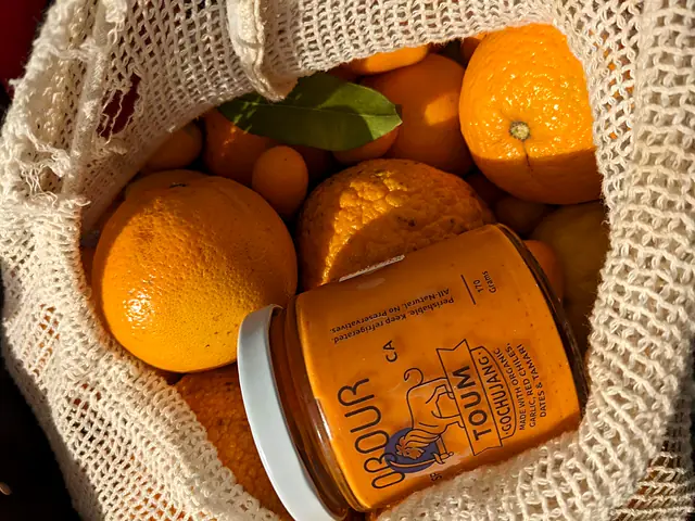 A jar of Obour Gochujang toum in a mesh bag full of oranges
