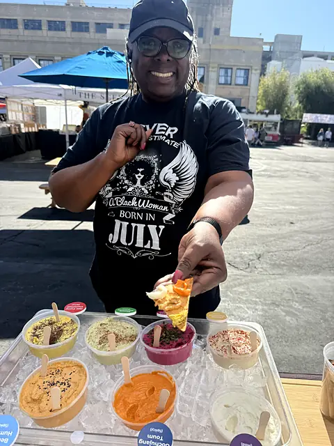 A team member holding out a sample on a pita chip over the sample tray
