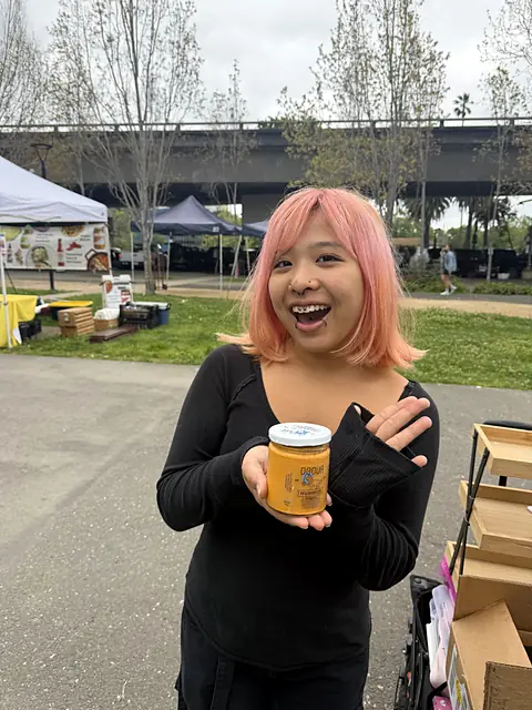 A delighted shopper holding a jar of Obour Hot Curry hummus