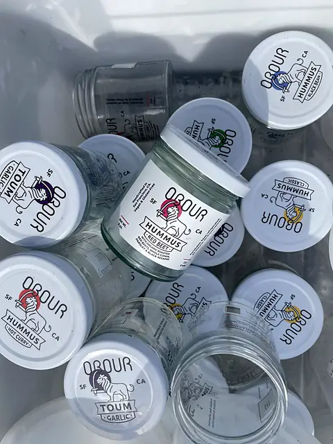 A bin of empty Obour glass jars with their lids, seen from above
