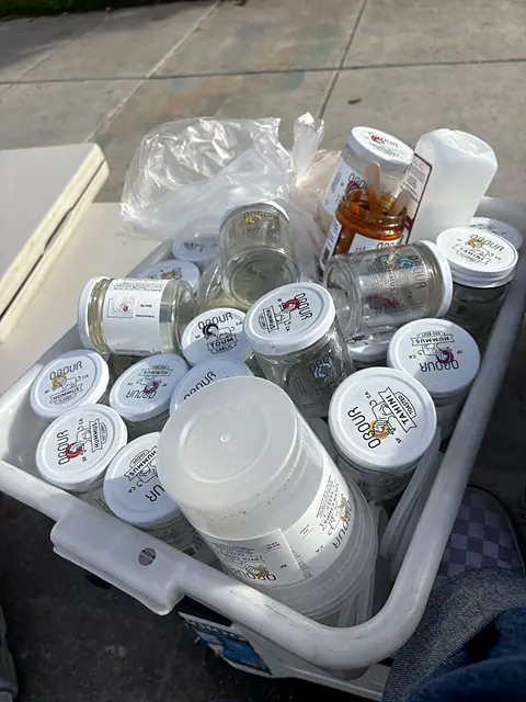 A crate of returned Obour glass jars and lids at a market stand