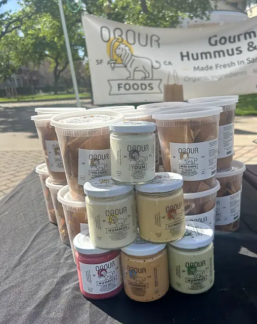 Obour jars and pita chip tubs stacked in front of the banner