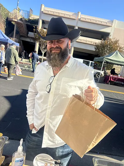 A shopper in a cowboy hat holding a full Obour bag