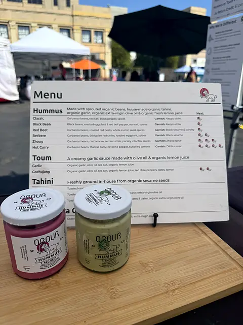 The Obour menu board with jars of Red Beet and Zhoug hummus in front