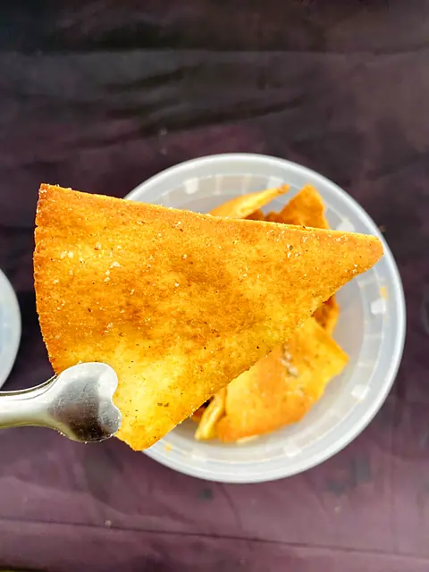 An Obour pita chip on a spoon over a bowl of chips