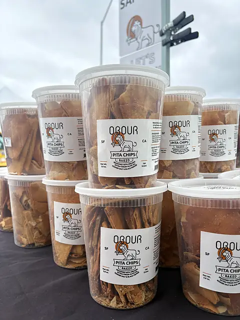 Tubs of Obour pita chips stacked by the samples sign