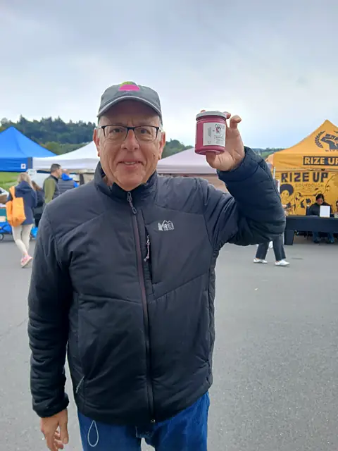 A shopper holding a jar of Obour Red Beet hummus up high at the market