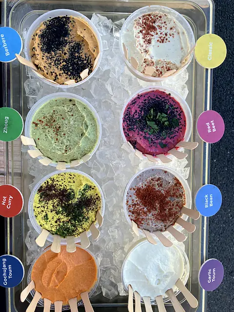 A labeled tray of Obour samples on ice with tasting spoons fanned out beside each tub