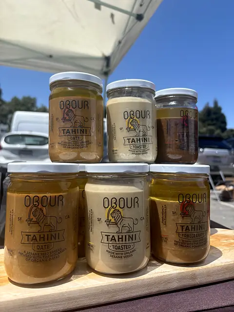 A pyramid of Obour tahini jars on a wooden board