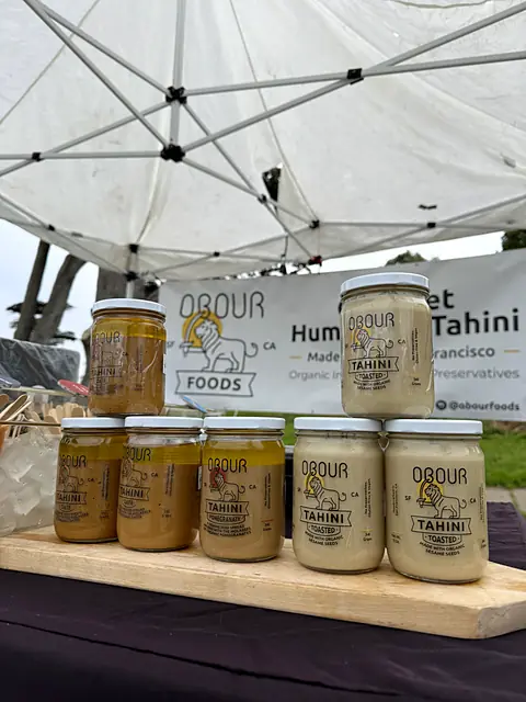 Jars of Obour tahini on a board in front of the Obour banner