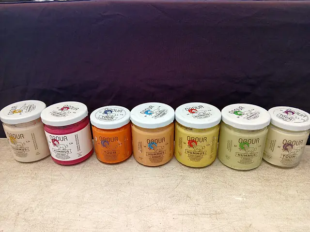 Seven jars of Obour hummus and toum in a row