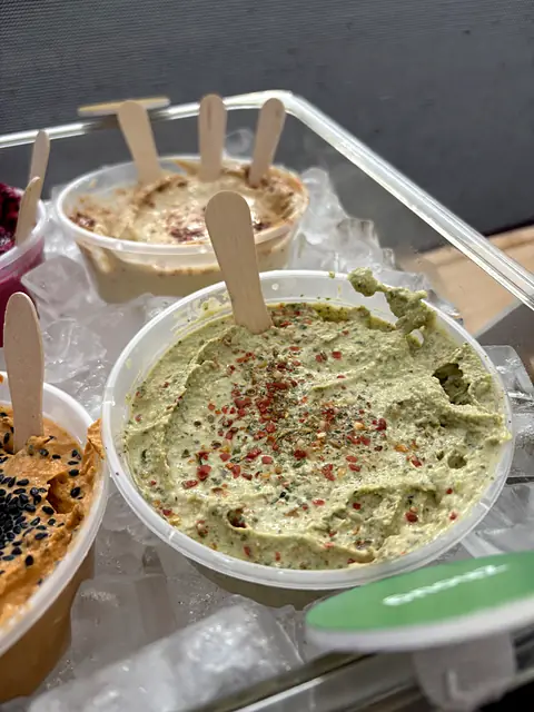 A tub of Obour Zhoug hummus with wooden tasting spoons