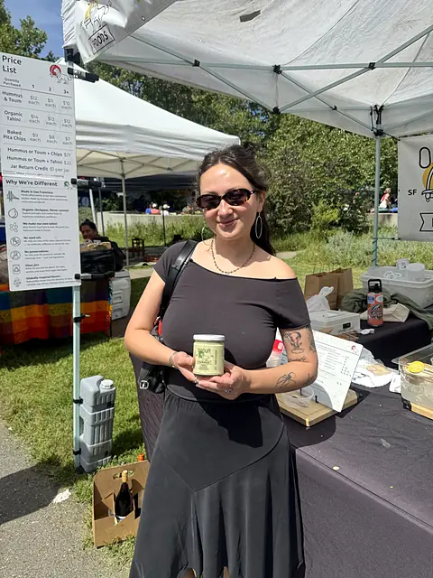 A shopper holding a jar of Obour Zhoug hummus at the market