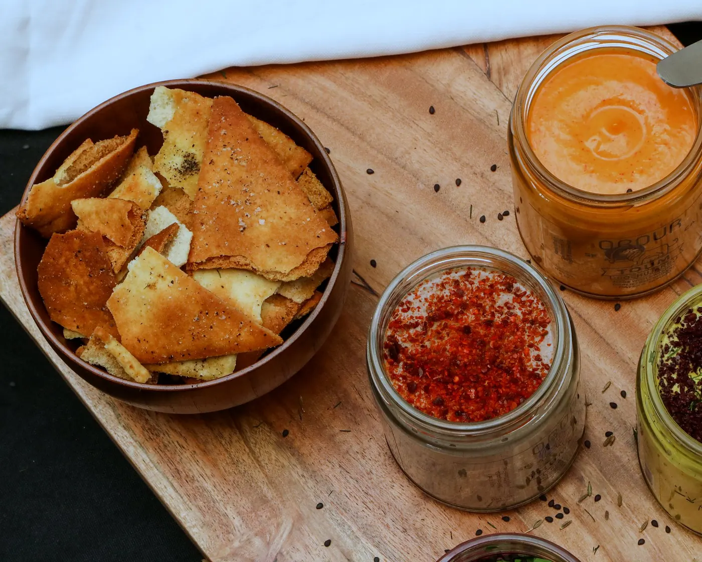 Gochujang toum, hummus and pita chips on a wooden board