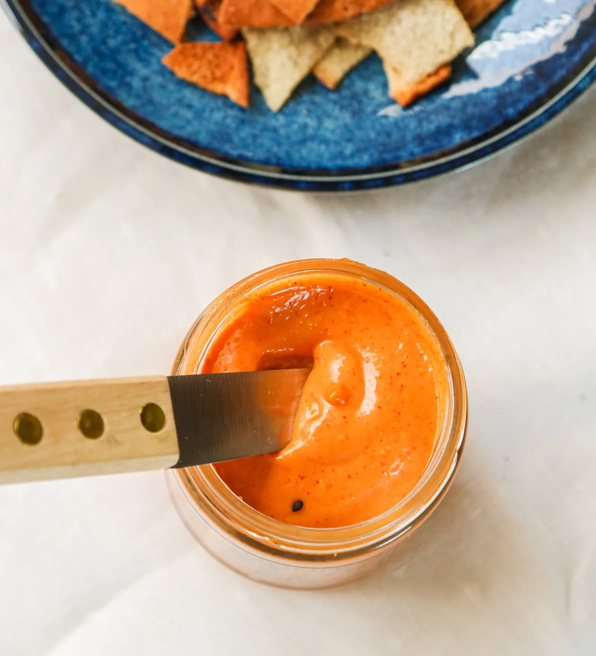A spreader in an open jar of Gochujang toum, seen from above