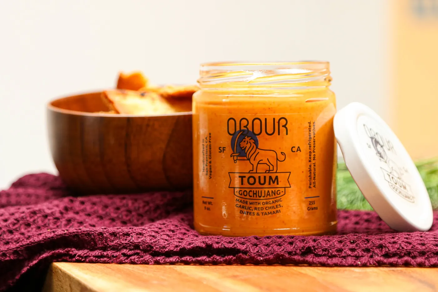 An open jar of Gochujang toum with its lid leaning against it