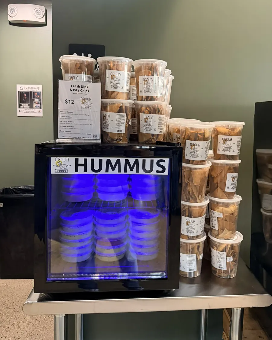An Obour Hummus Fridge with its menu card and stacks of pita chip tubs