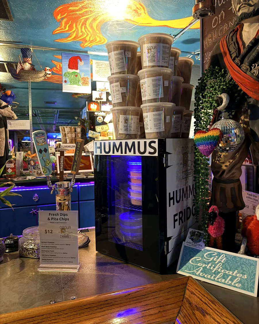 An Obour Hummus Fridge stocked with dips and pita chips on a bar