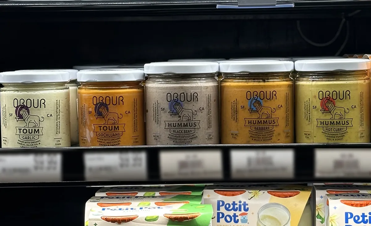 Obour toum and hummus jars on a grocery store refrigerated shelf