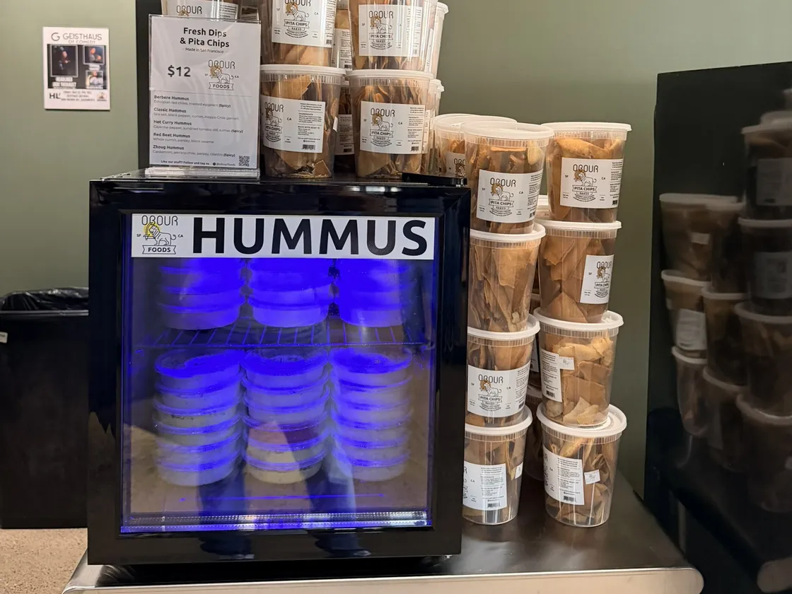 A newly installed Obour Hummus Fridge with its menu card and tubs of pita chips