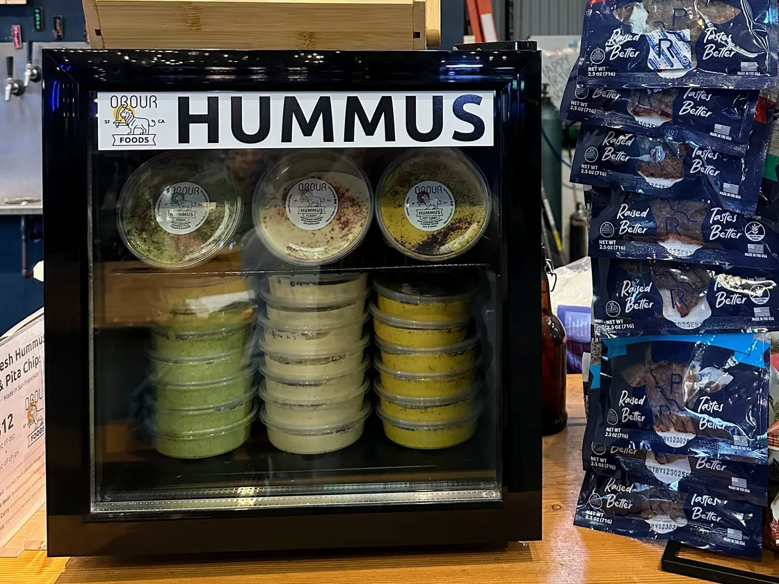 An Obour Hummus Fridge stocked with tubs of hummus and toum